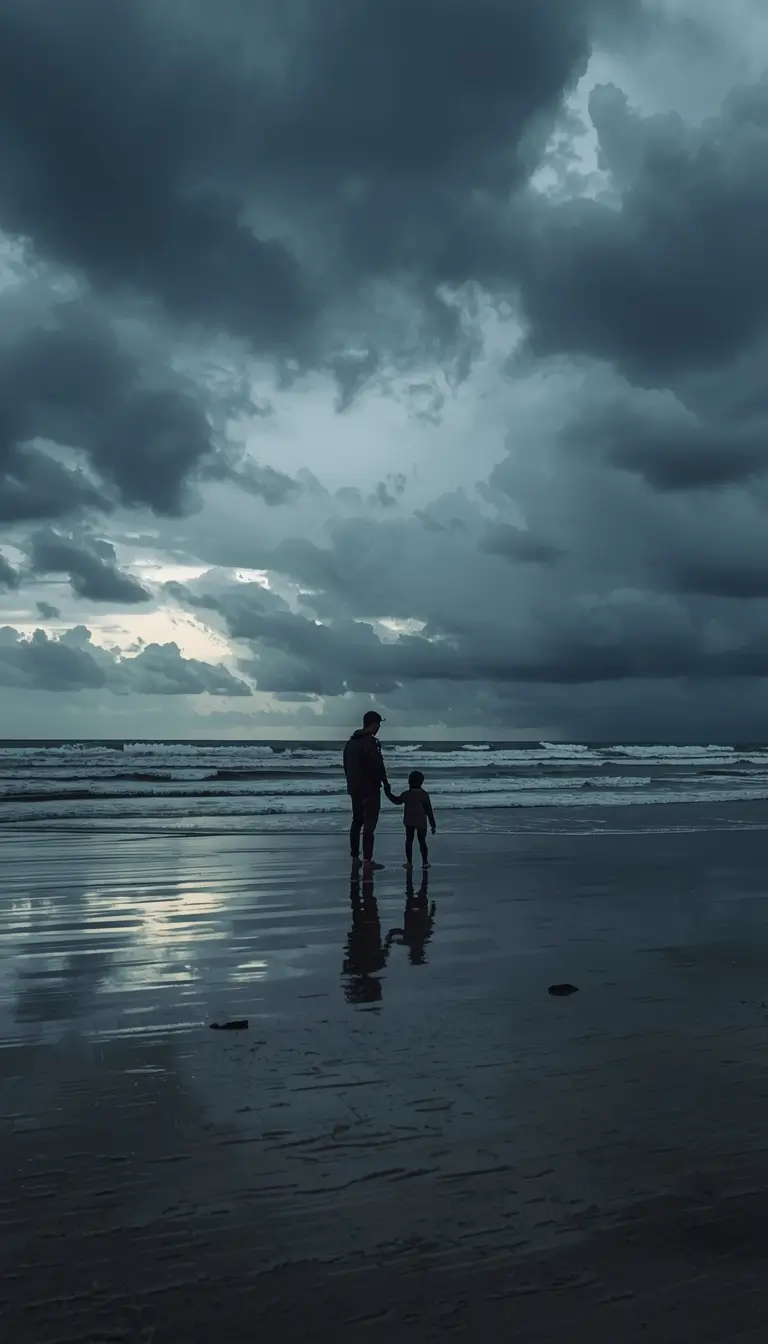 Family photos on the beach showing a parent and child holding hands at the shoreline under a moody sky with reflective wet sand.