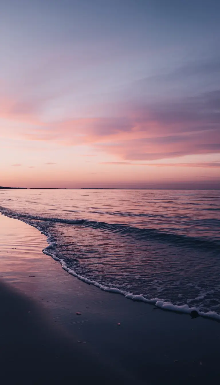 Calm ocean shoreline at sunset with gentle waves and pastel sky, ideal nature wallpaper for desktop and phone
