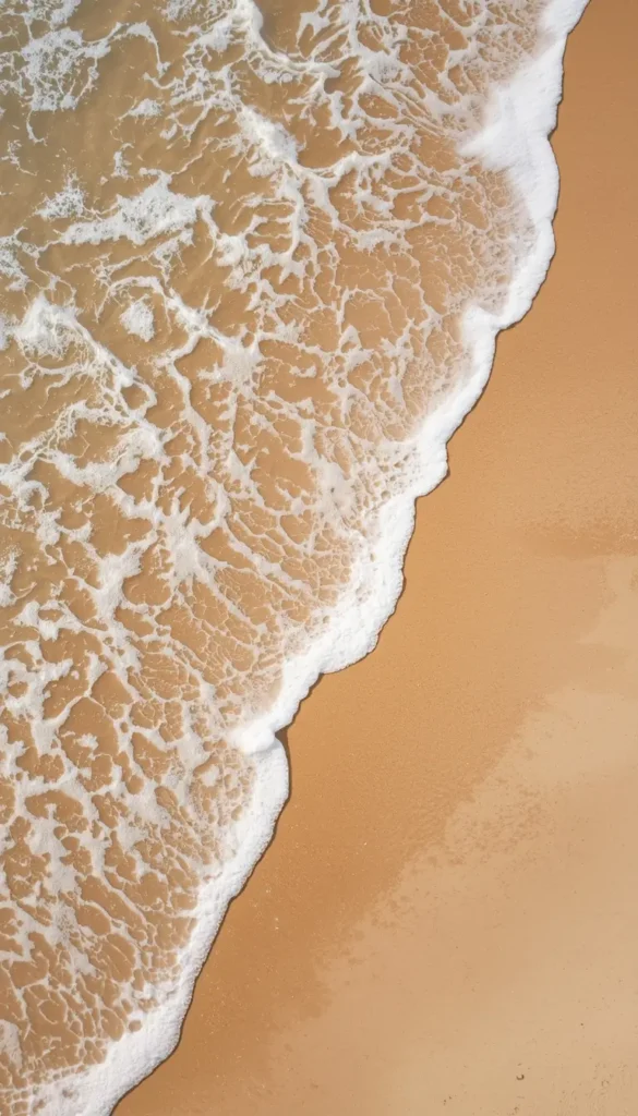 aerial view of beach waves on sand summer iphone wallpaper with soft foam and warm tones