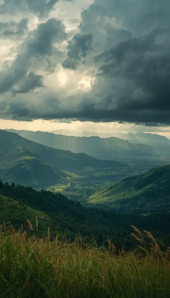 Dark storm clouds over green mountain valley with sun rays shining through cinematic nature-wallpaper for desktop and phone